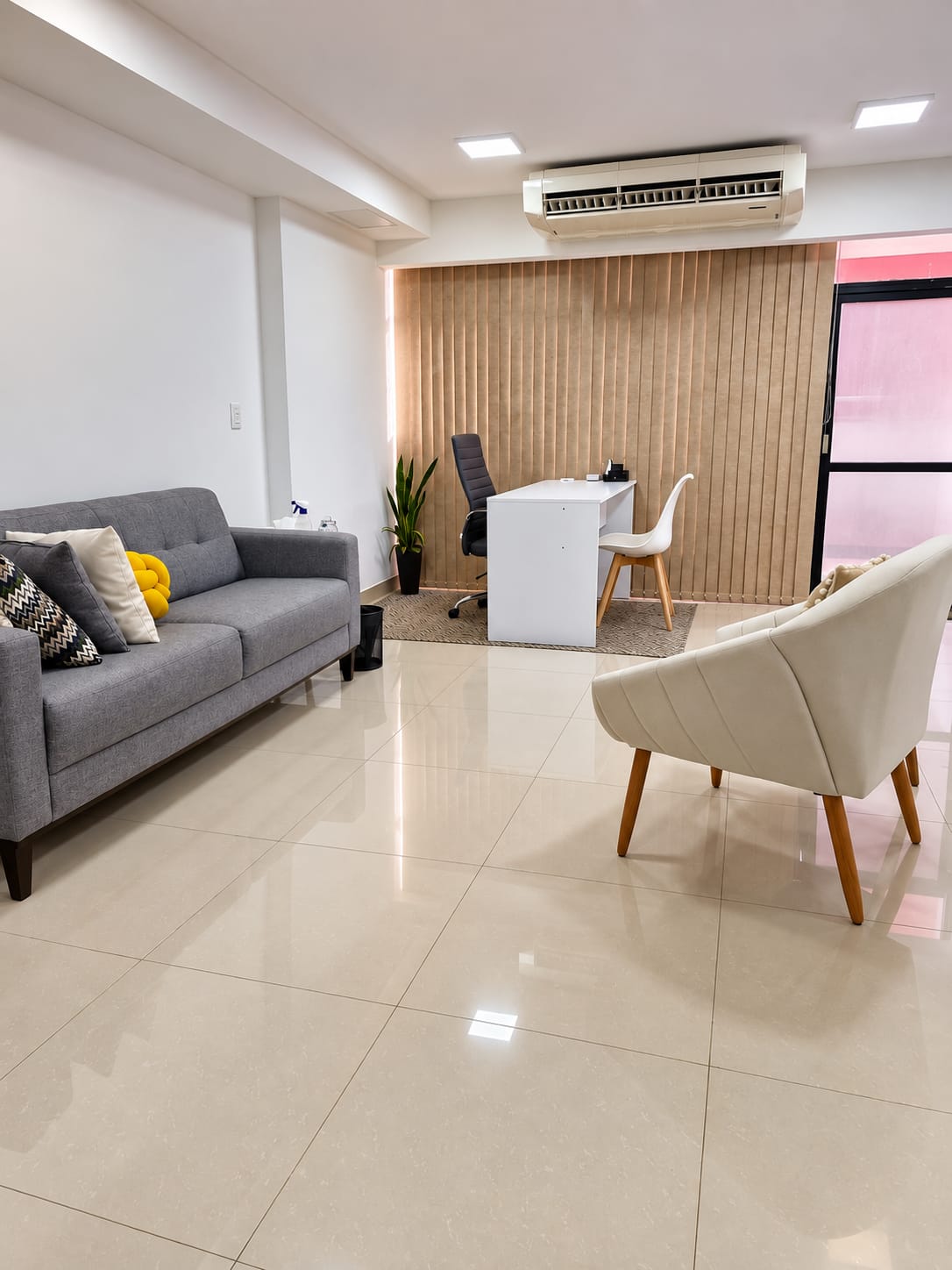 Consultório em Brasília com sofá cinza, poltrona e mesa de atendimento