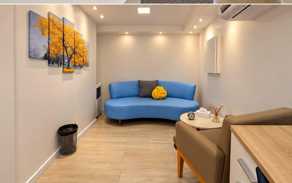 Sala de atendimento com sofá azul e quadro de árvore